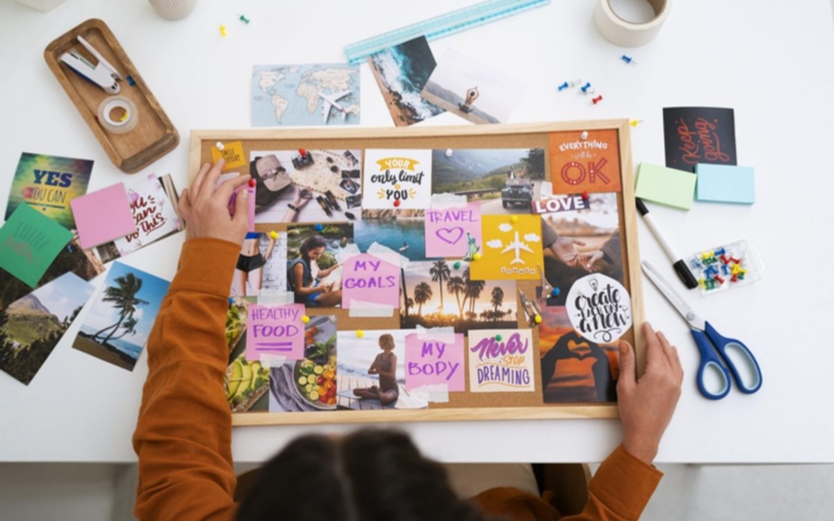 Tableau de visualisation en cours de création : photos et mots collés sur un panneau de liège